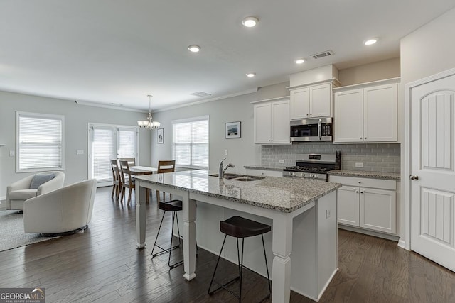 kitchen featuring stainless steel appliances, a sink, a center island with sink, and white cabinets