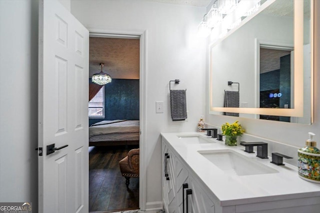 bathroom with double vanity, ensuite bathroom, a sink, and wood finished floors