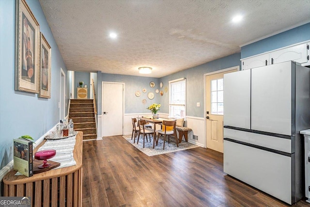 kitchen with a wainscoted wall, dark wood finished floors, freestanding refrigerator, white cabinetry, and a textured ceiling