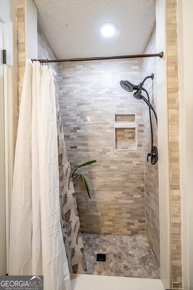 full bathroom featuring a tile shower and a textured ceiling