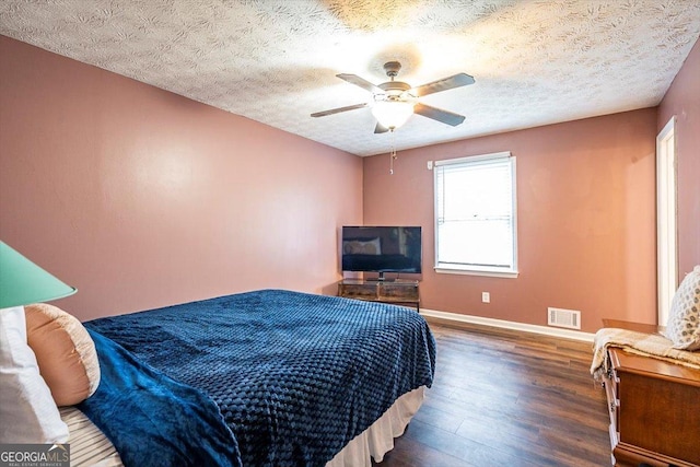 bedroom with baseboards, visible vents, a ceiling fan, dark wood finished floors, and a textured ceiling