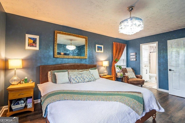 bedroom with ensuite bathroom, a textured ceiling, dark wood-type flooring, baseboards, and an inviting chandelier