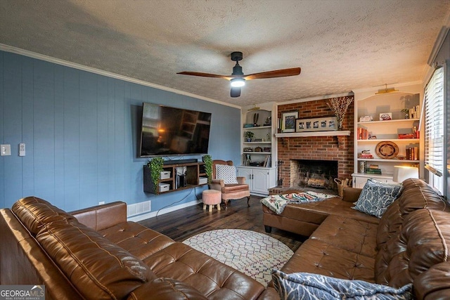 living area with a textured ceiling, a fireplace, visible vents, ornamental molding, and dark wood finished floors