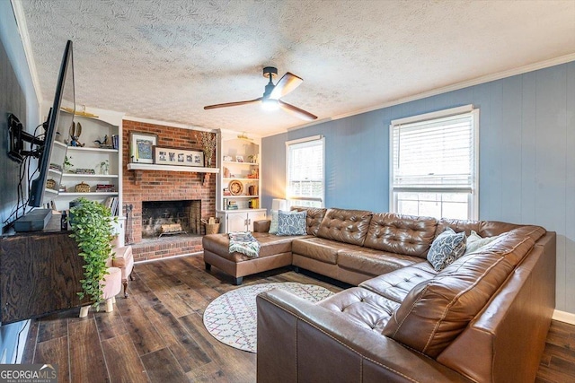 living area with a ceiling fan, a brick fireplace, dark wood finished floors, and a textured ceiling