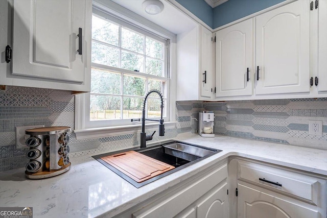 kitchen featuring a sink, tasteful backsplash, white cabinets, and light countertops