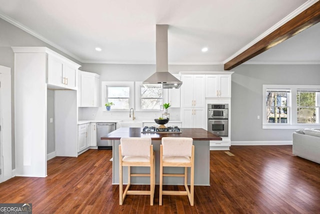 kitchen featuring white cabinets, a kitchen island, appliances with stainless steel finishes, a kitchen breakfast bar, and a sink