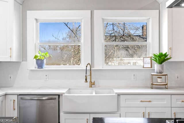 kitchen featuring dishwasher, decorative backsplash, a sink, and white cabinets