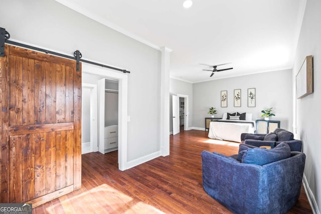 living room featuring dark wood-style floors, a barn door, ornamental molding, a ceiling fan, and baseboards