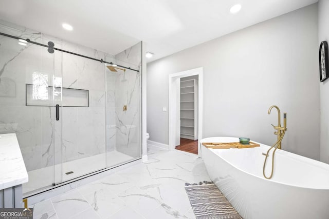 bathroom with a marble finish shower, toilet, a soaking tub, marble finish floor, and recessed lighting