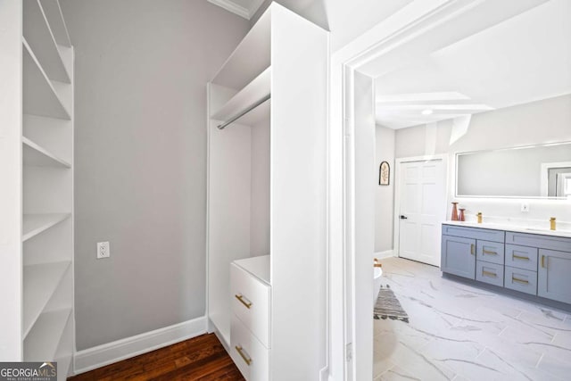 interior space featuring double vanity, marble finish floor, and baseboards