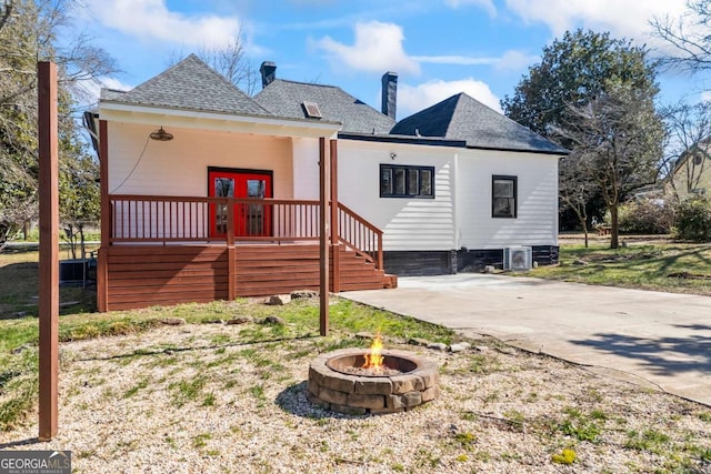 back of property featuring a shingled roof, an outdoor fire pit, french doors, and a chimney