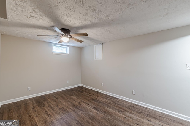 empty room with a textured ceiling, ceiling fan, dark wood-style flooring, and baseboards