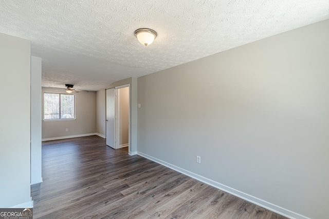 spare room featuring a textured ceiling, baseboards, and dark wood-type flooring