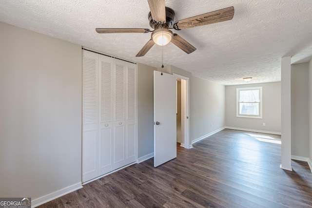 unfurnished bedroom featuring ceiling fan, a textured ceiling, dark wood-type flooring, baseboards, and a closet