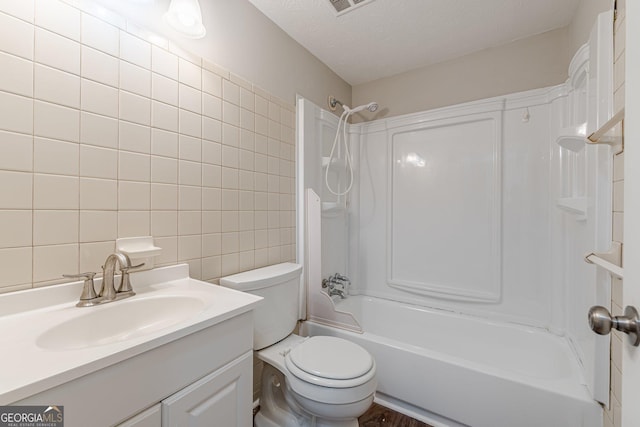 full bath featuring a textured ceiling, toilet, vanity, tile walls, and tub / shower combination