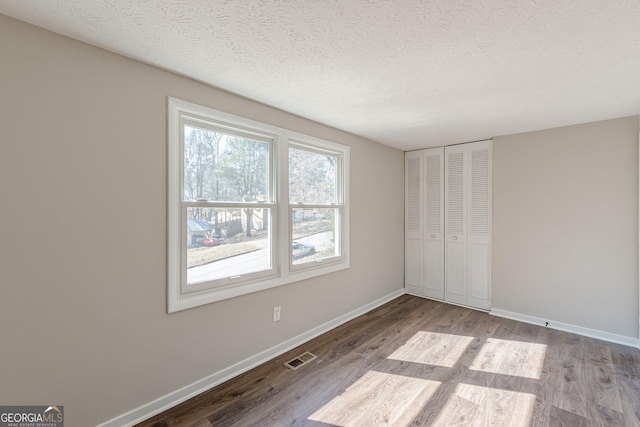 unfurnished bedroom with light wood-type flooring, visible vents, baseboards, and a textured ceiling