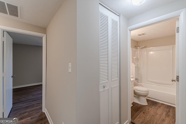 corridor with visible vents, dark wood finished floors, and a textured ceiling