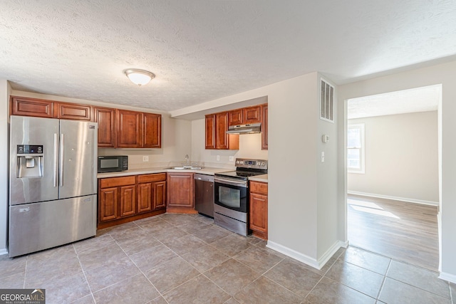 kitchen featuring light countertops, visible vents, appliances with stainless steel finishes, a sink, and under cabinet range hood