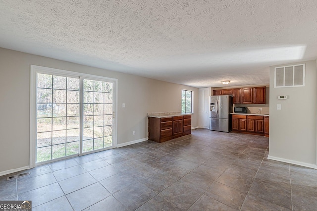 interior space with brown cabinetry, black microwave, visible vents, and stainless steel fridge with ice dispenser