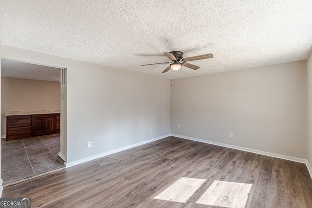 spare room with ceiling fan, dark wood-type flooring, and baseboards