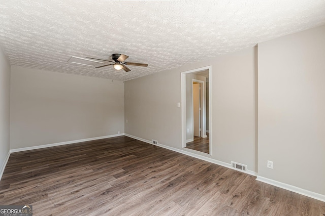 unfurnished room with visible vents, dark wood finished floors, a textured ceiling, and baseboards