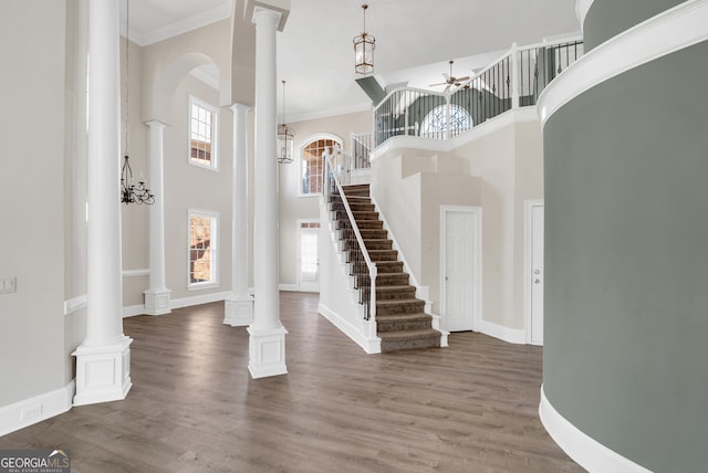 entryway with dark wood-style flooring, ornate columns, ornamental molding, ceiling fan, and baseboards