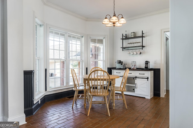 dining area featuring brick floor, baseboards, ornamental molding, and a chandelier