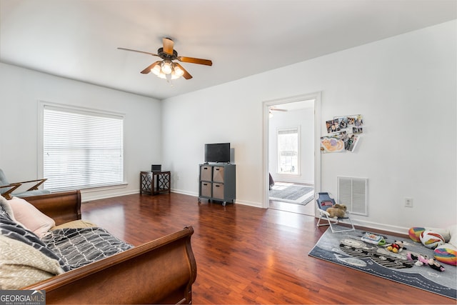 living area featuring baseboards, dark wood finished floors, visible vents, and a ceiling fan