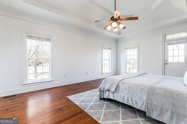 bedroom featuring dark wood-style floors, baseboards, a tray ceiling, and ornamental molding