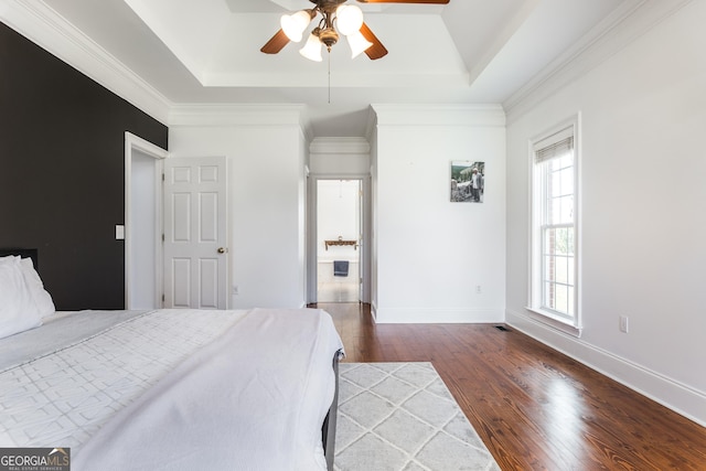 bedroom featuring dark wood-style floors, baseboards, and a tray ceiling