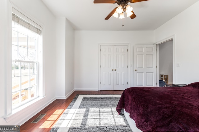 bedroom with wood finished floors, a ceiling fan, visible vents, baseboards, and a closet