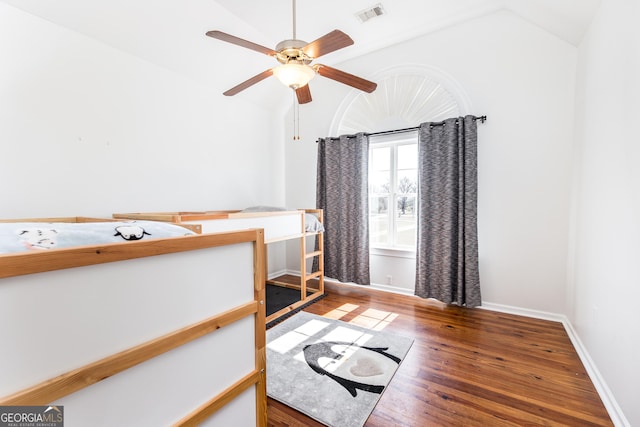 bedroom featuring baseboards, visible vents, vaulted ceiling, and wood finished floors