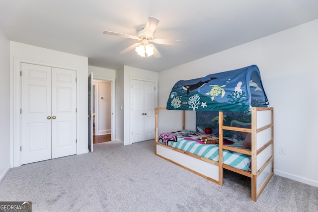 carpeted bedroom featuring ceiling fan, baseboards, and two closets