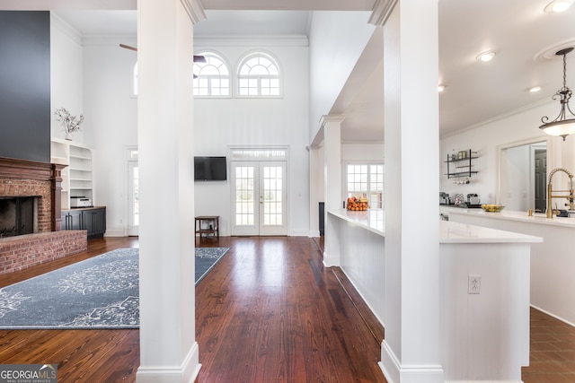 foyer with dark wood-style floors, french doors, a fireplace, and crown molding