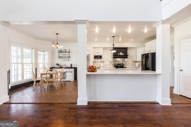 kitchen featuring light countertops, black fridge, white cabinetry, and decorative light fixtures