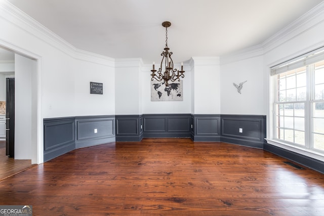 unfurnished dining area featuring an inviting chandelier, visible vents, ornamental molding, and dark wood-style flooring