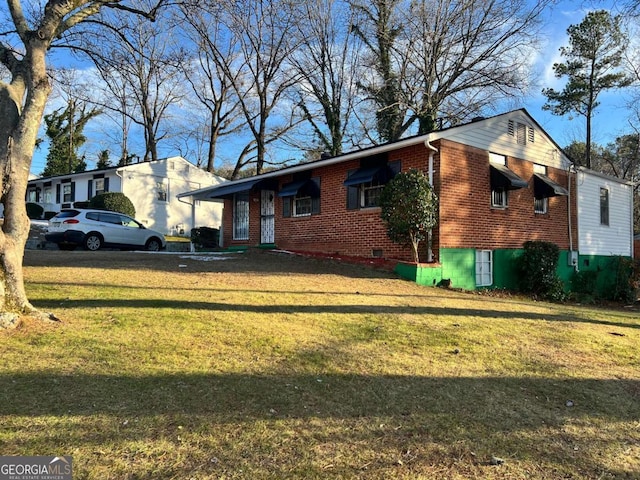 view of front facade with brick siding and a front lawn