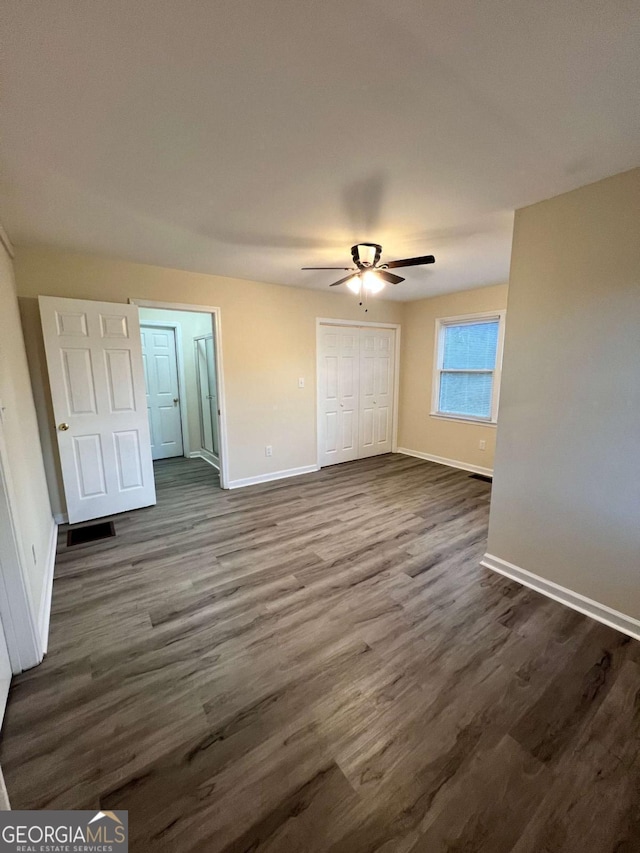 unfurnished bedroom with a closet, visible vents, dark wood finished floors, and baseboards