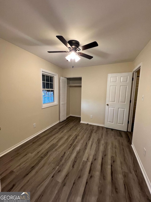 unfurnished bedroom with a closet, dark wood finished floors, a ceiling fan, and baseboards