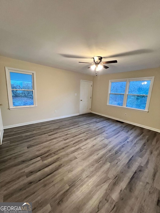 interior space featuring dark wood-type flooring, a ceiling fan, visible vents, and baseboards