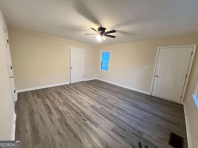 unfurnished bedroom with a ceiling fan, dark wood-style flooring, visible vents, and baseboards