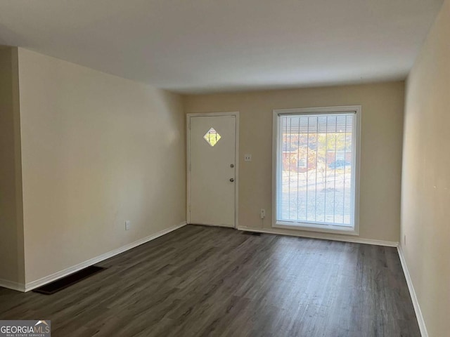 foyer entrance featuring dark wood-style flooring, visible vents, and baseboards