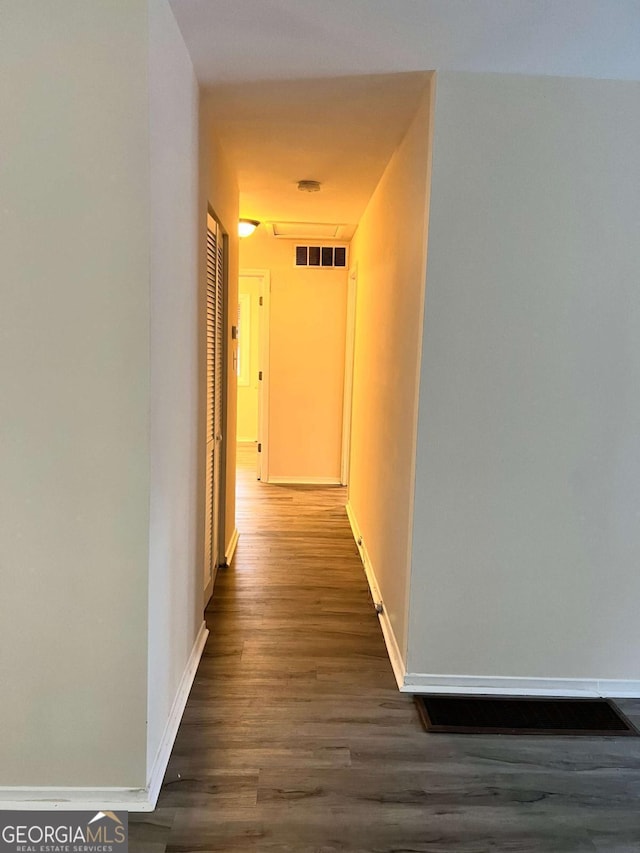 hallway featuring dark wood-style floors, visible vents, and baseboards