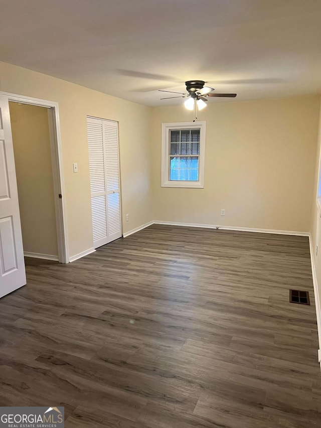 unfurnished bedroom featuring a closet, dark wood-style flooring, visible vents, and baseboards