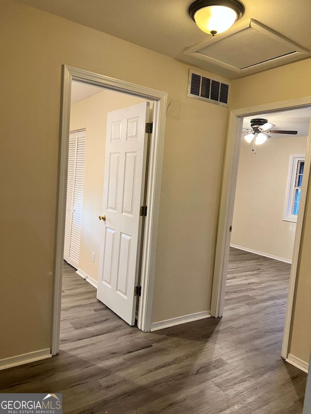 hallway with dark wood-style flooring, visible vents, and baseboards