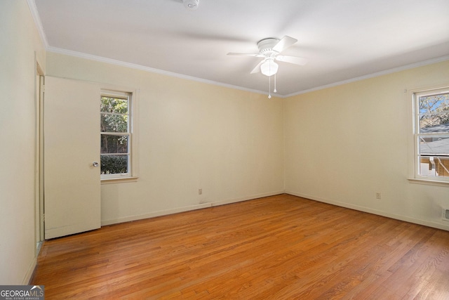 spare room featuring light wood finished floors, a wealth of natural light, and crown molding