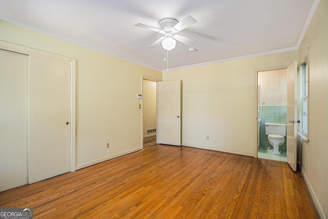 unfurnished bedroom featuring visible vents, a ceiling fan, connected bathroom, ornamental molding, and wood finished floors