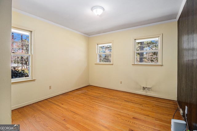 spare room with ornamental molding, light wood-type flooring, and visible vents