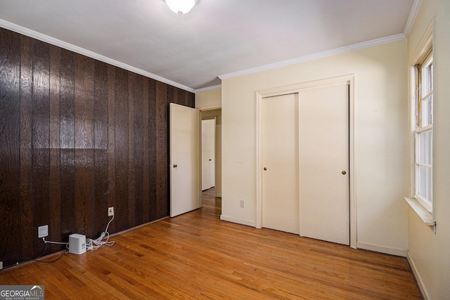 unfurnished bedroom with light wood finished floors, a closet, baseboards, and crown molding