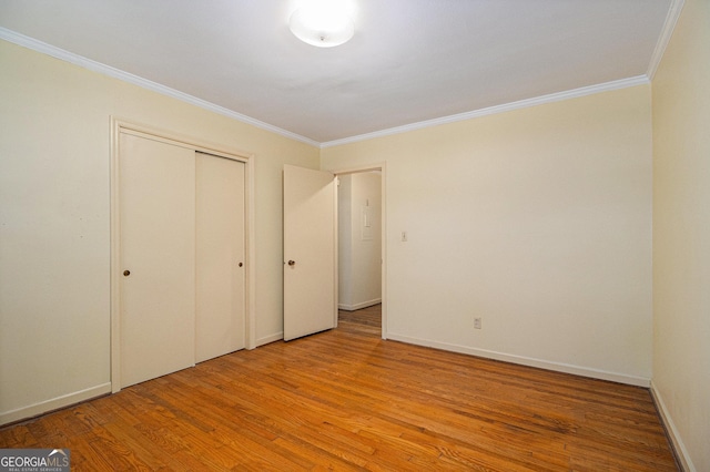 unfurnished bedroom with ornamental molding, a closet, light wood-style flooring, and baseboards